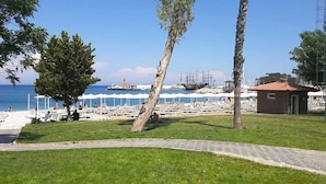 Een kustgebied met een grasrijk pad, een klein gebouw en een jachthaven met boten.