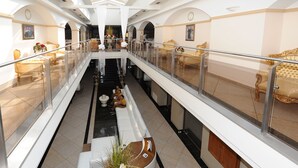 Un vestíbulo amplio con una zona de estar central, una escalera y un balcón con asientos.