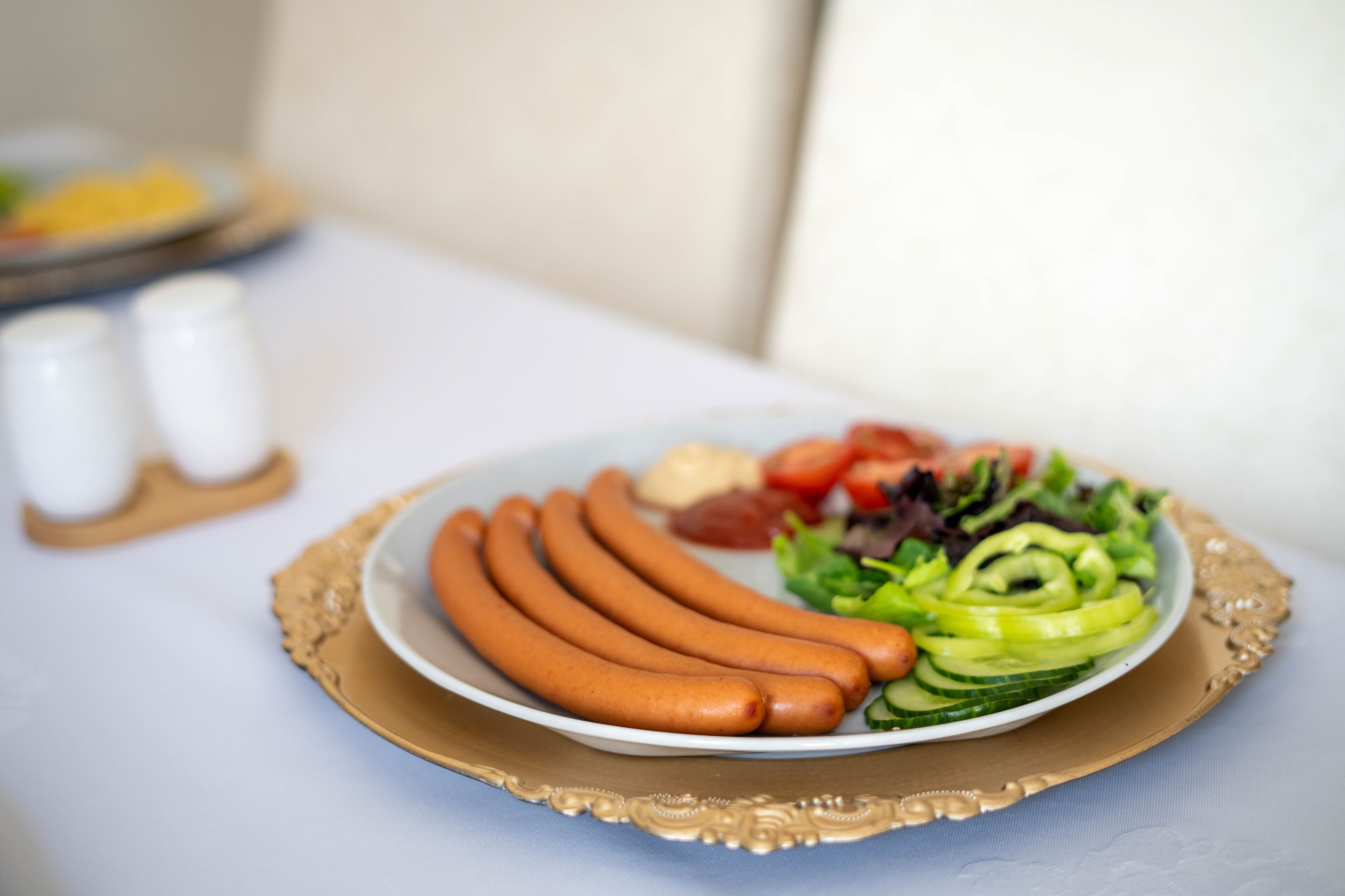 Un plato de salchichas y ensalada sobre una mesa.