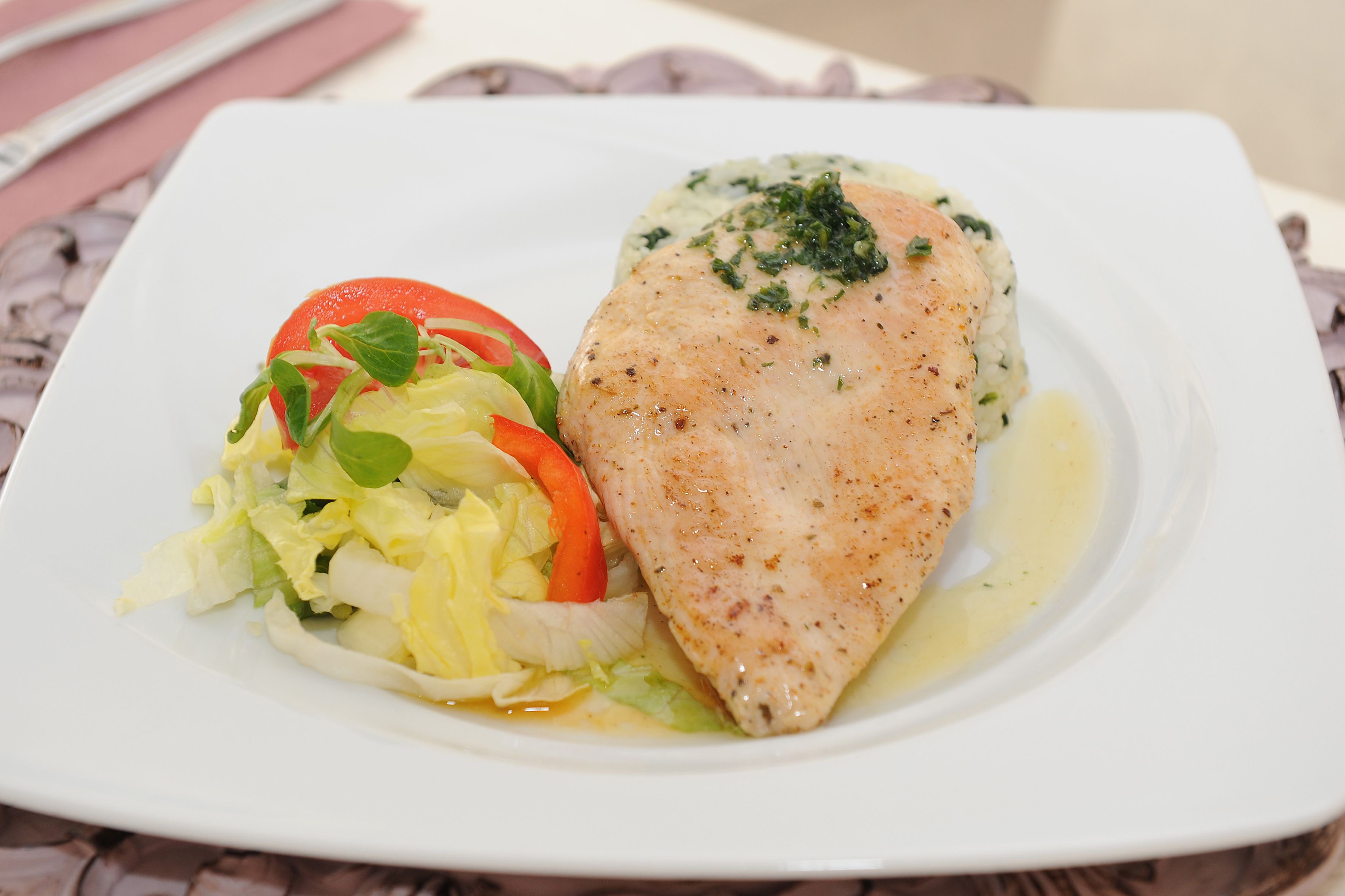 A plate with a piece of fish, a side salad, and a creamy sauce.