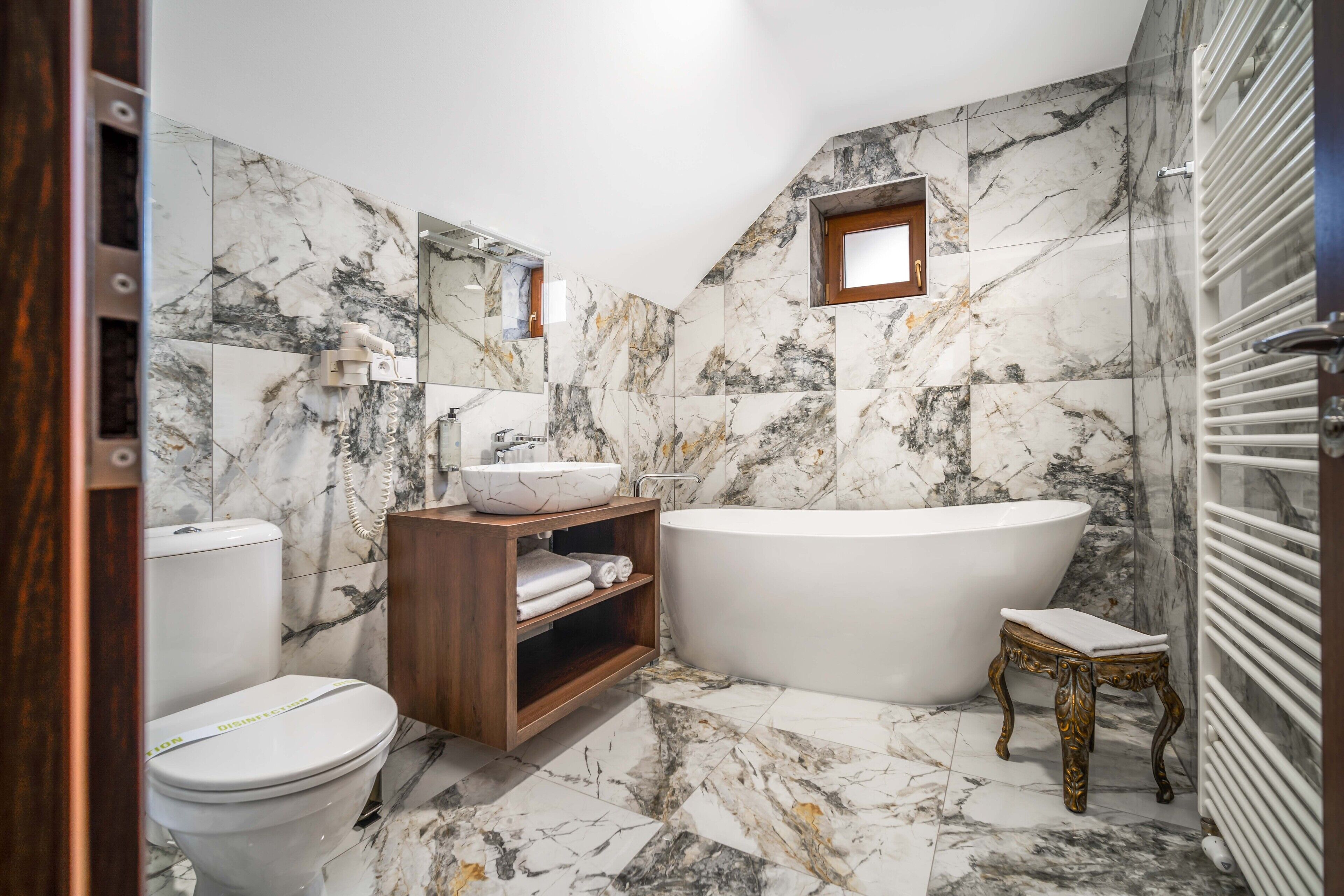 Un bany amb una banyera autònoma, un vàter i un lavabo amb respatller de marbre.