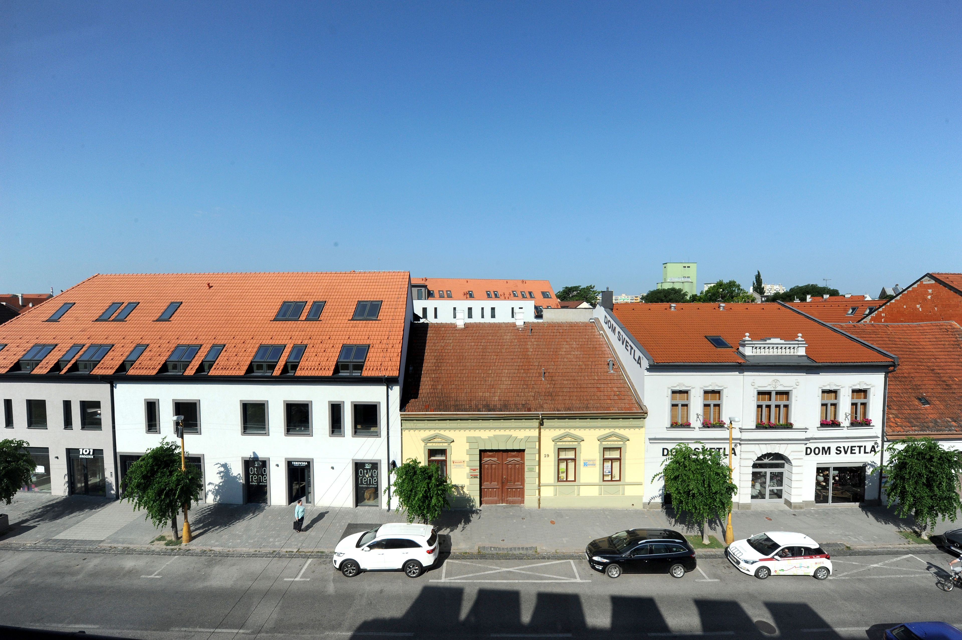 Straßenansicht mit Gebäuden, Autos und blauem Himmel.