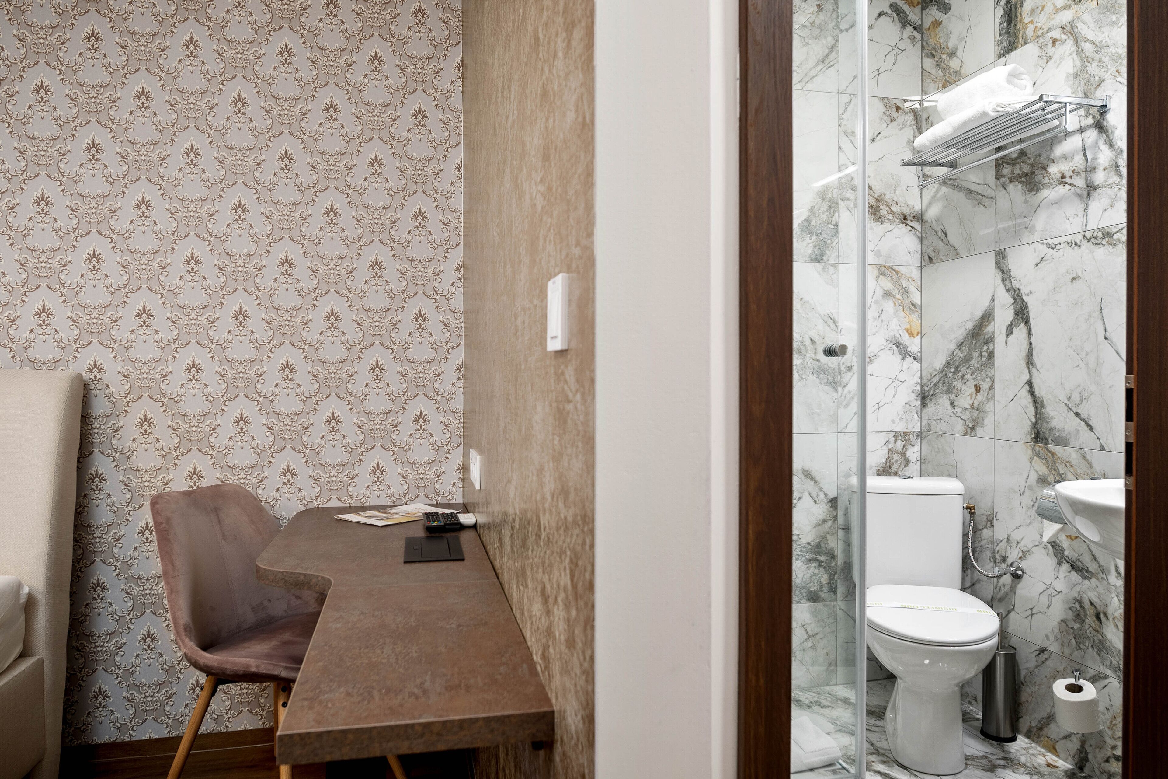 A bathroom with a toilet, marble tiles, and a shower area.