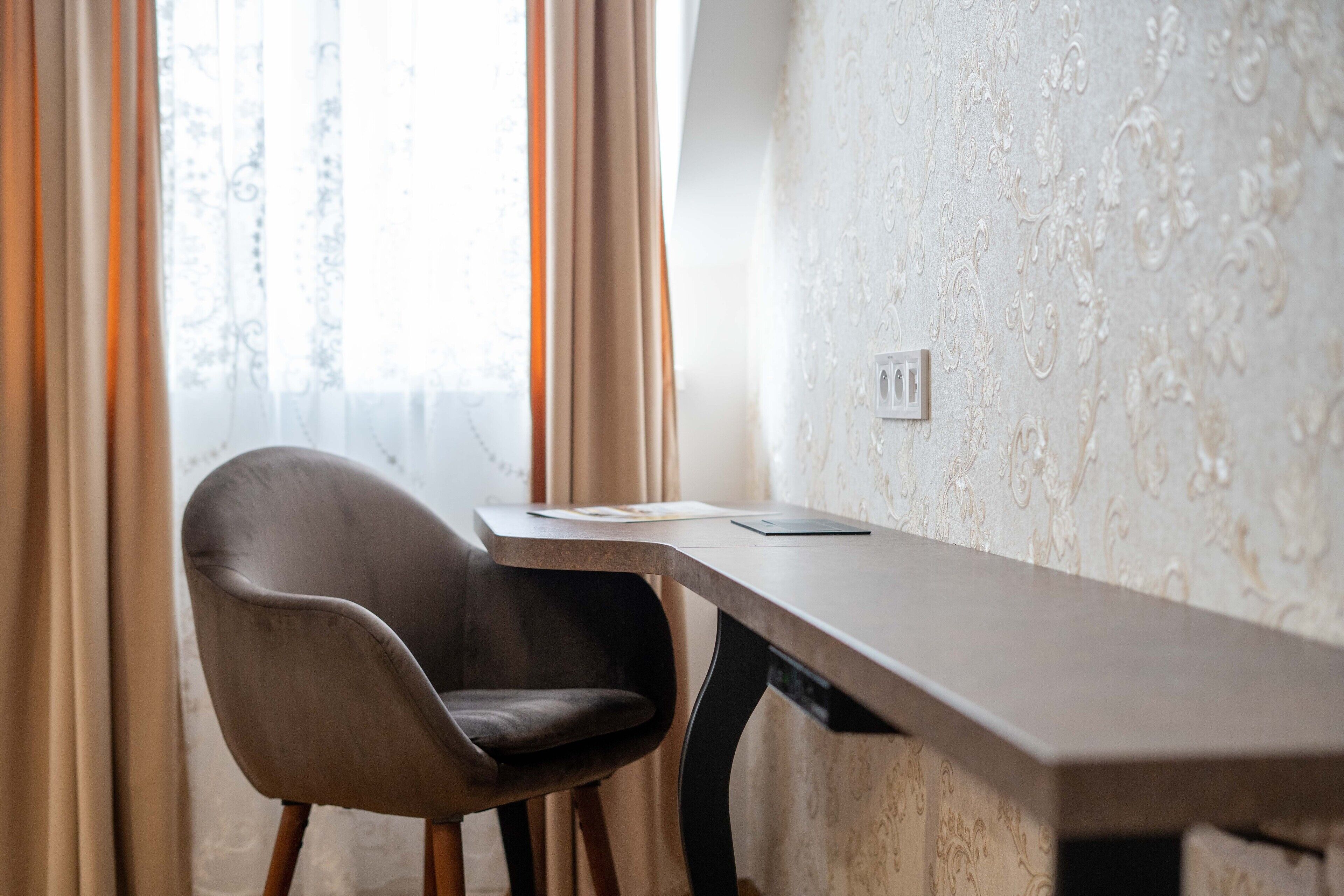 A modern room with a desk, chair, and patterned wallpaper.