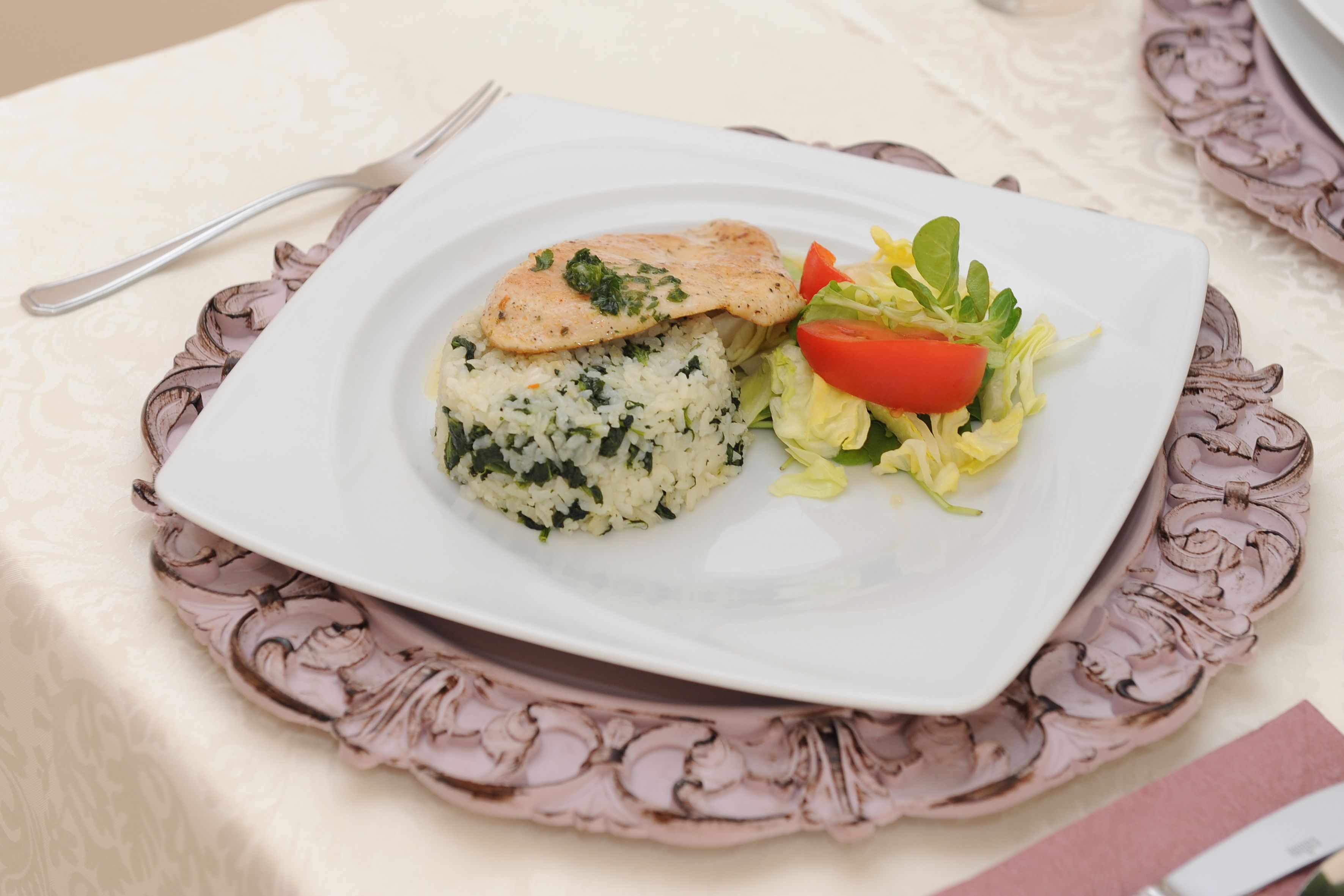Un piatto di cibo con salmone, riso e un'insalata come contorno, su un piatto decorativo.