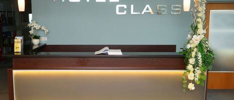A hotel reception desk with a modern design, featuring a wooden counter and a glass panel.