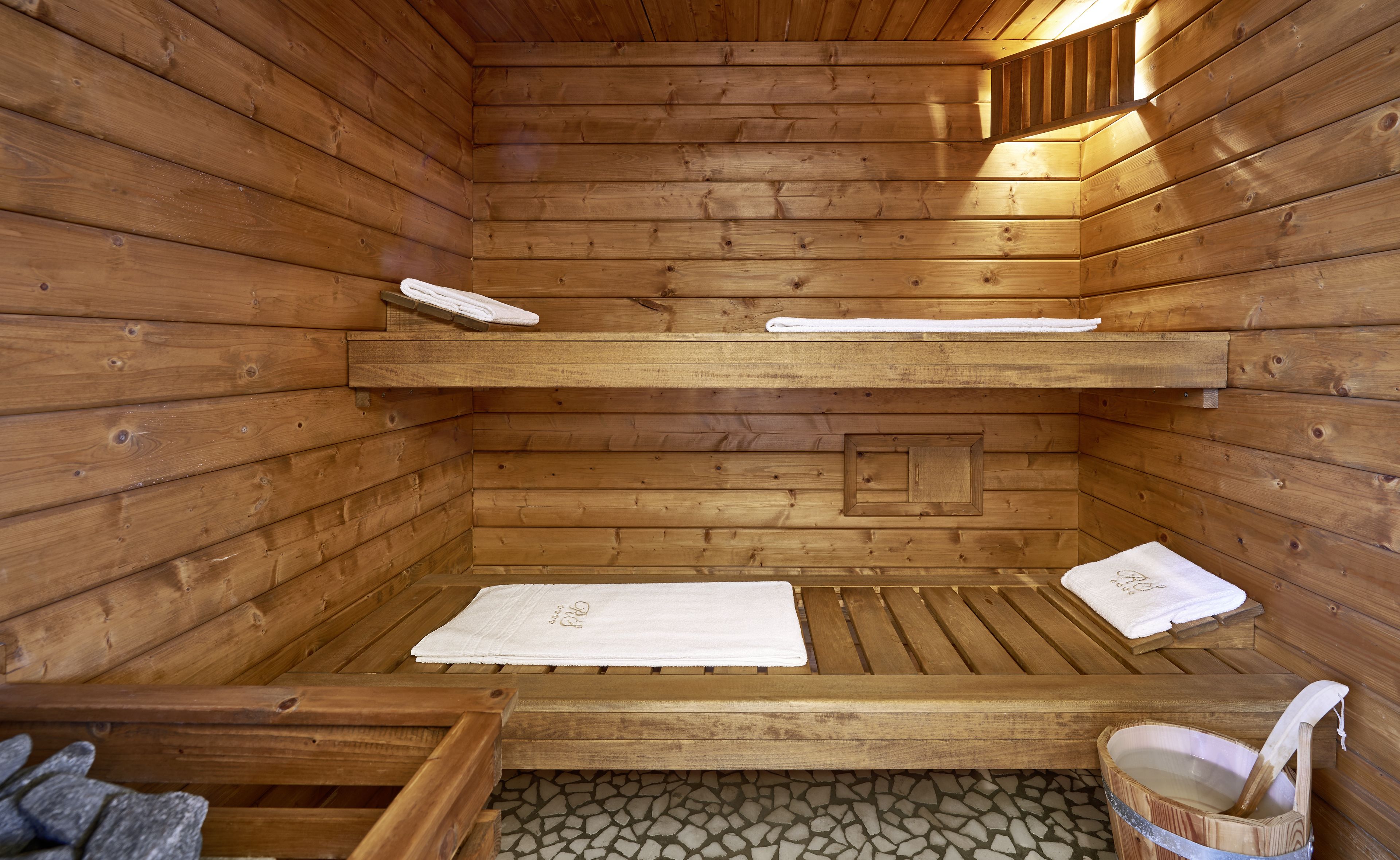 Una sauna de madera con bancos y suelo de piedra.