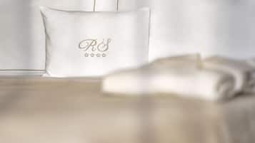 Un lit avec un oreiller blanc orné d’un monogramme et de cinq étoiles.