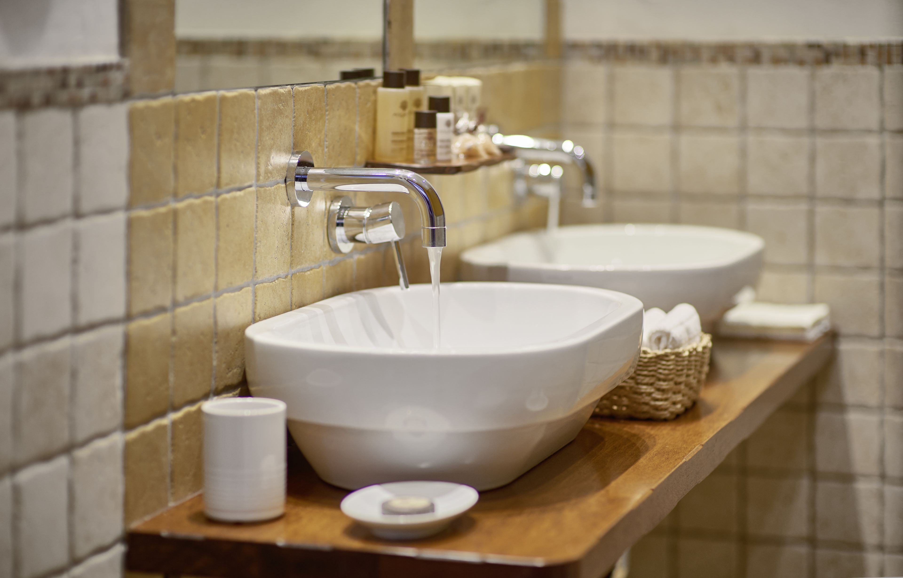 A bathroom with two sinks, a mirror, and toiletries on the counter.