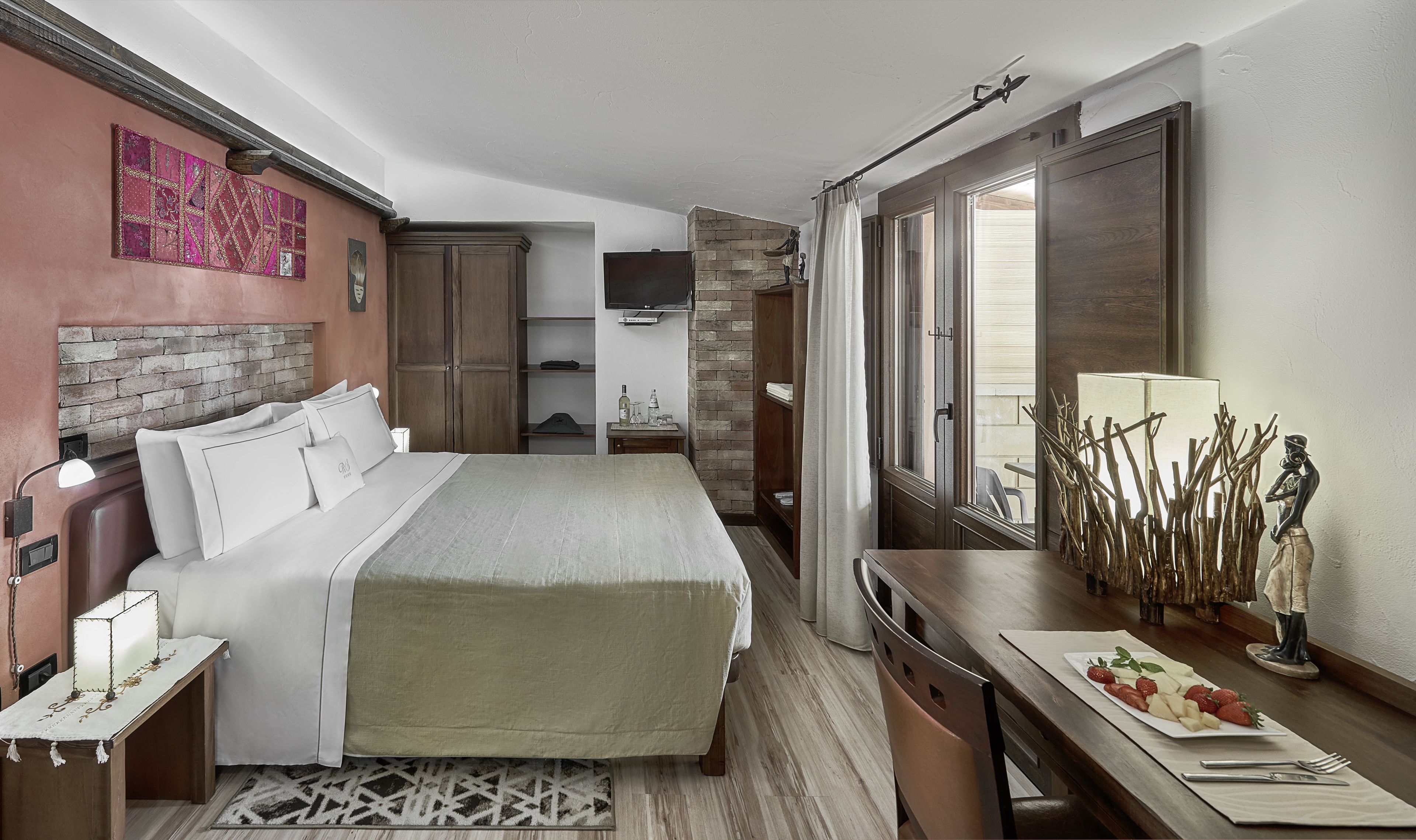 A bedroom with a bed, bedside table, lamp, dresser, and a dining area with a table set for two.