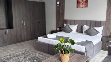 Een moderne slaapkamer met een groot bed, een houten nachtkastje, een bijzettafeltje, een hanglamp en een schilderij aan de muur.