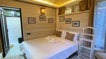 Un dormitorio con una cama grande, techo de madera y cuadros enmarcados en la pared.