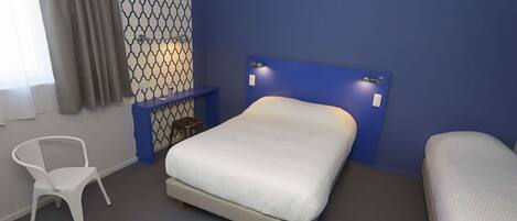 A bedroom with a bed, a chair, and a small table.