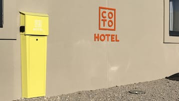Ein Hotelschild mit einem gelben Briefkasten und einer Grünanlage davor.