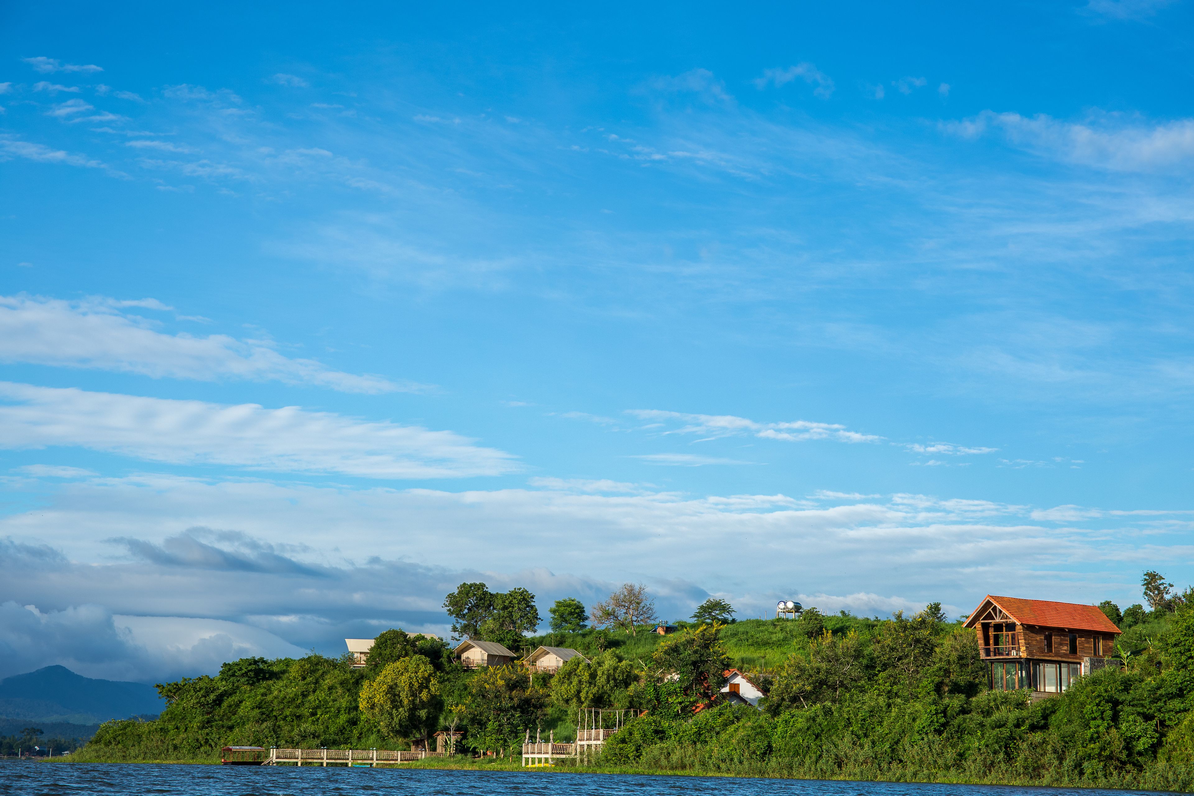 A lakeside property with a wooden house, a dock, and lush greenery.