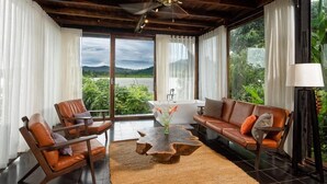 A modern living room with leather sofas, a coffee table, and a view of a lake. - Lak Tented Camp (Lak)
