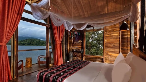 A room with a bed, curtains, and a view of a lake. - Lak Tented Camp (Lak)