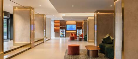 A modern lobby with a TV, seating area, and vending machines.