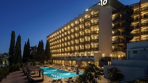 A hotel with a swimming pool, multiple balconies, and a well-lit facade.