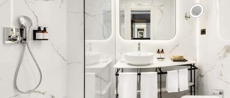 Un baño moderno con ducha de vidrio, tocador con lavamanos y espejo, y un bidé.