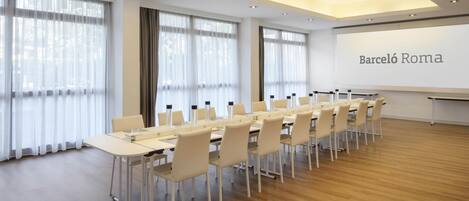 A conference room with a long table, chairs, and a projector screen displaying 'Barceló Roma'.
