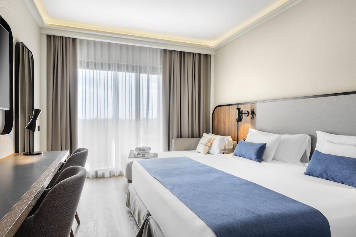 A hotel room with a large bed, a desk, and a chair.