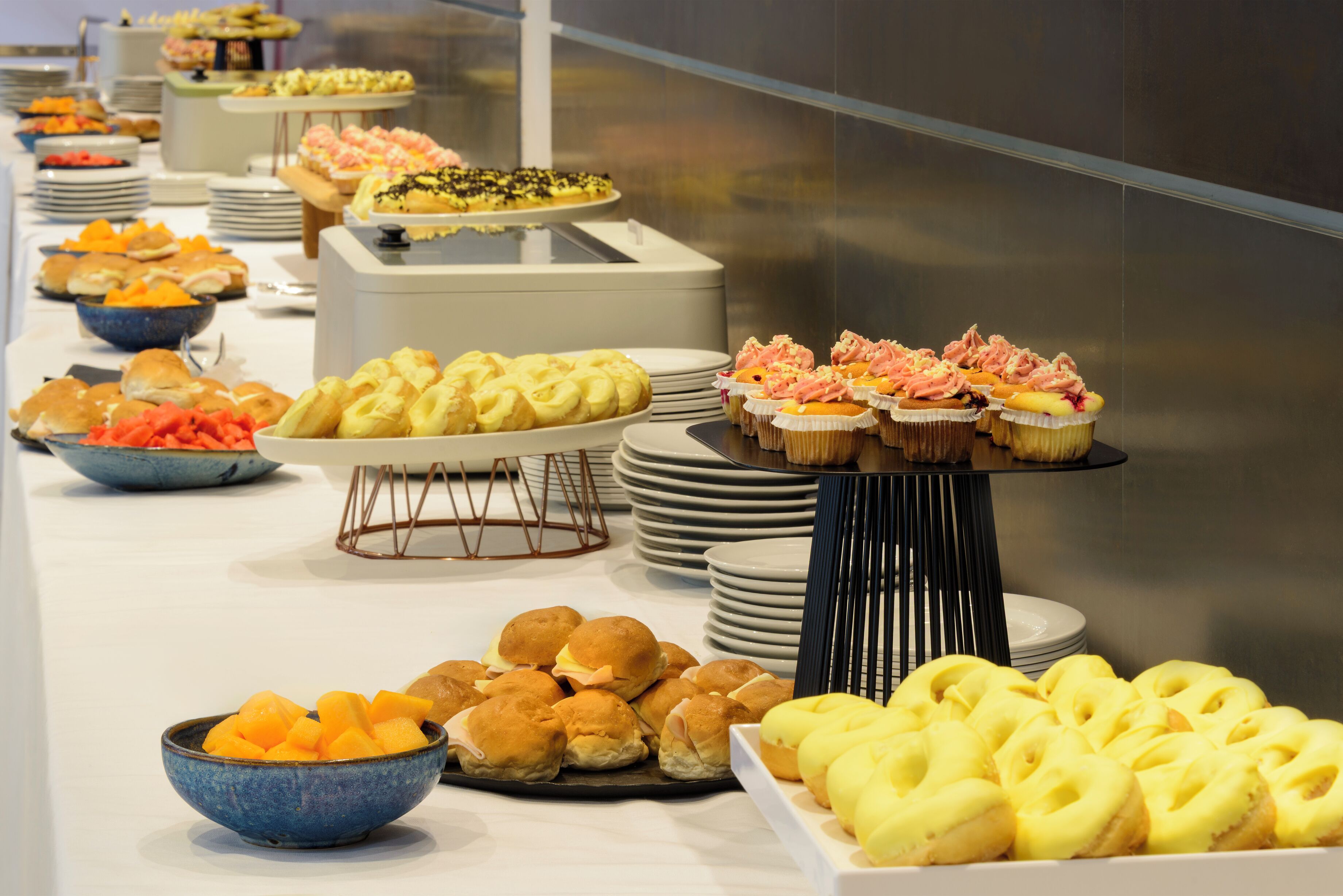Een buffet met diverse soorten eten, waaronder gebak, fruit en belegde broodjes.