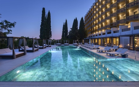 A swimming pool with lounge chairs and a building with balconies.