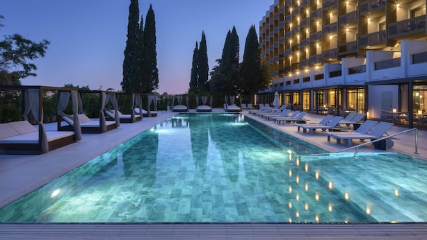 A swimming pool with lounge chairs and a building with balconies.