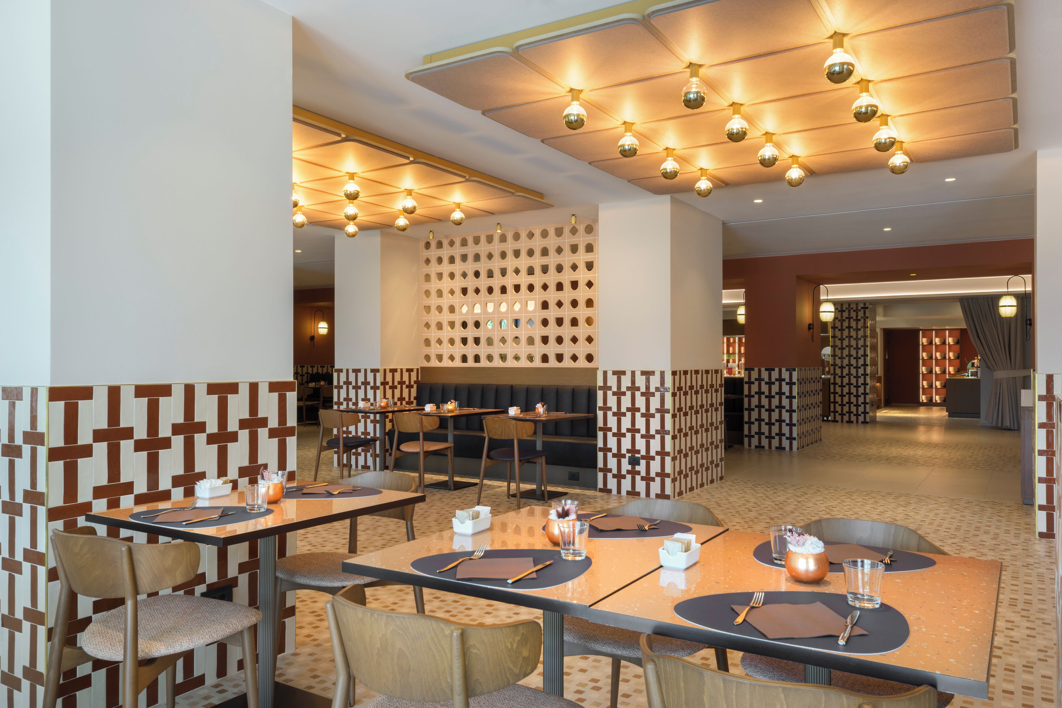 A restaurant with multiple tables, chairs, and a patterned wall.