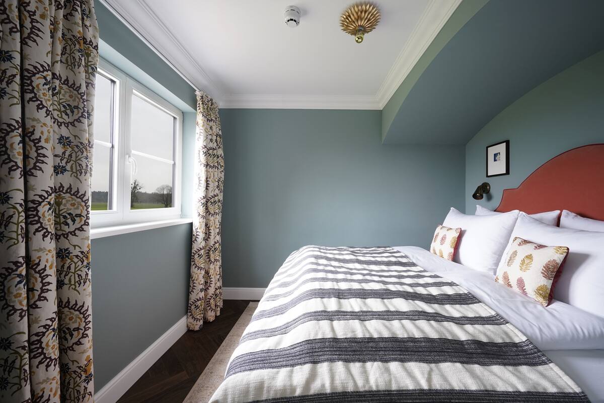 Quarto com cama, cortinas e janela.