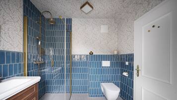 Et badeværelse med bruser, toilet og håndvask.