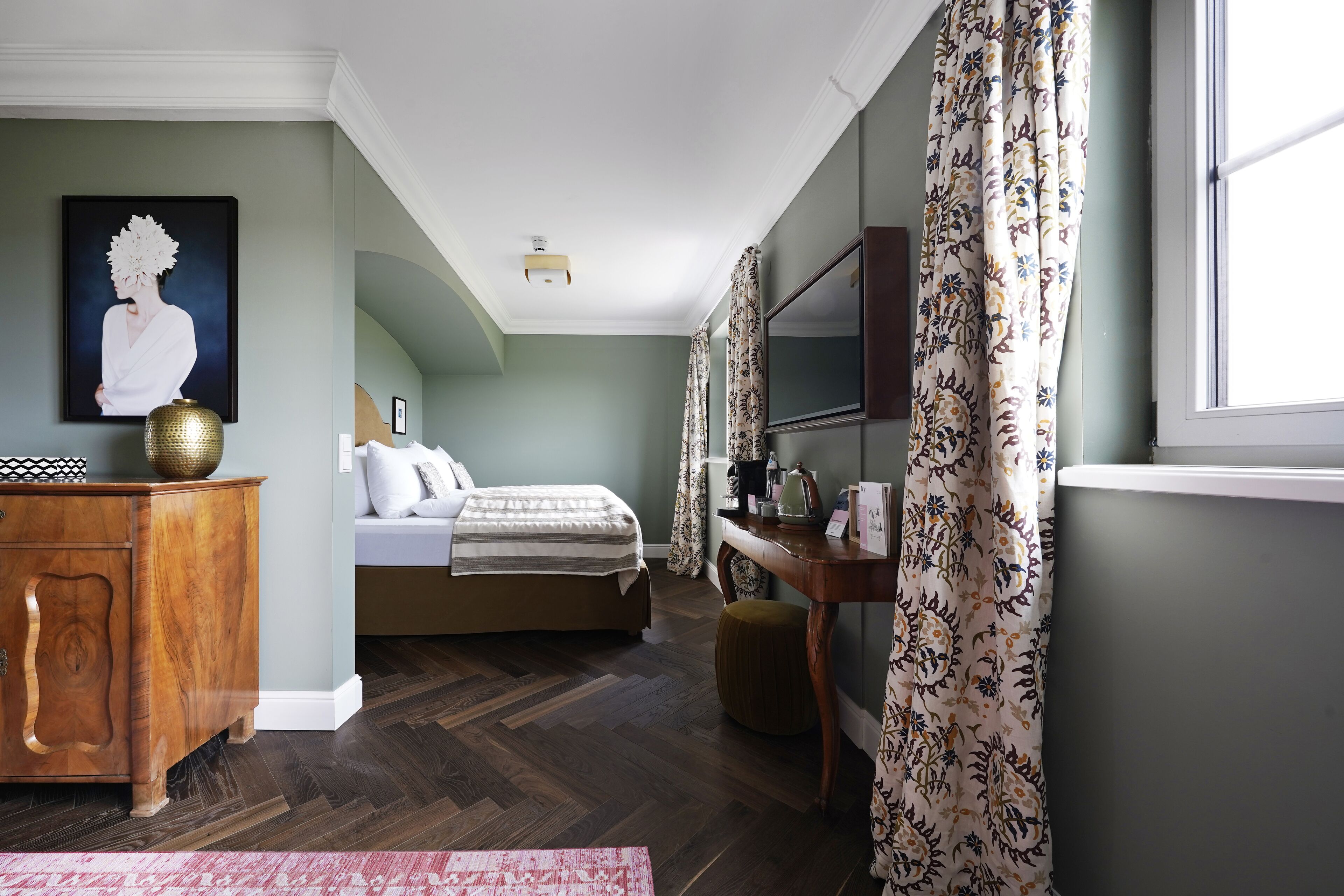 A bedroom with a bed, dresser, and a painting on the wall.