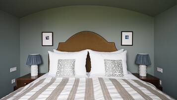 Un letto rifatto con cura, una coperta a righe, due lampade ai lati e una testiera con un decoro.