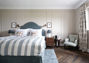 A neatly arranged bedroom with a large bed, bedside tables, a chair, and a patterned curtain. - Numa Salzburg Ivy (Anif)