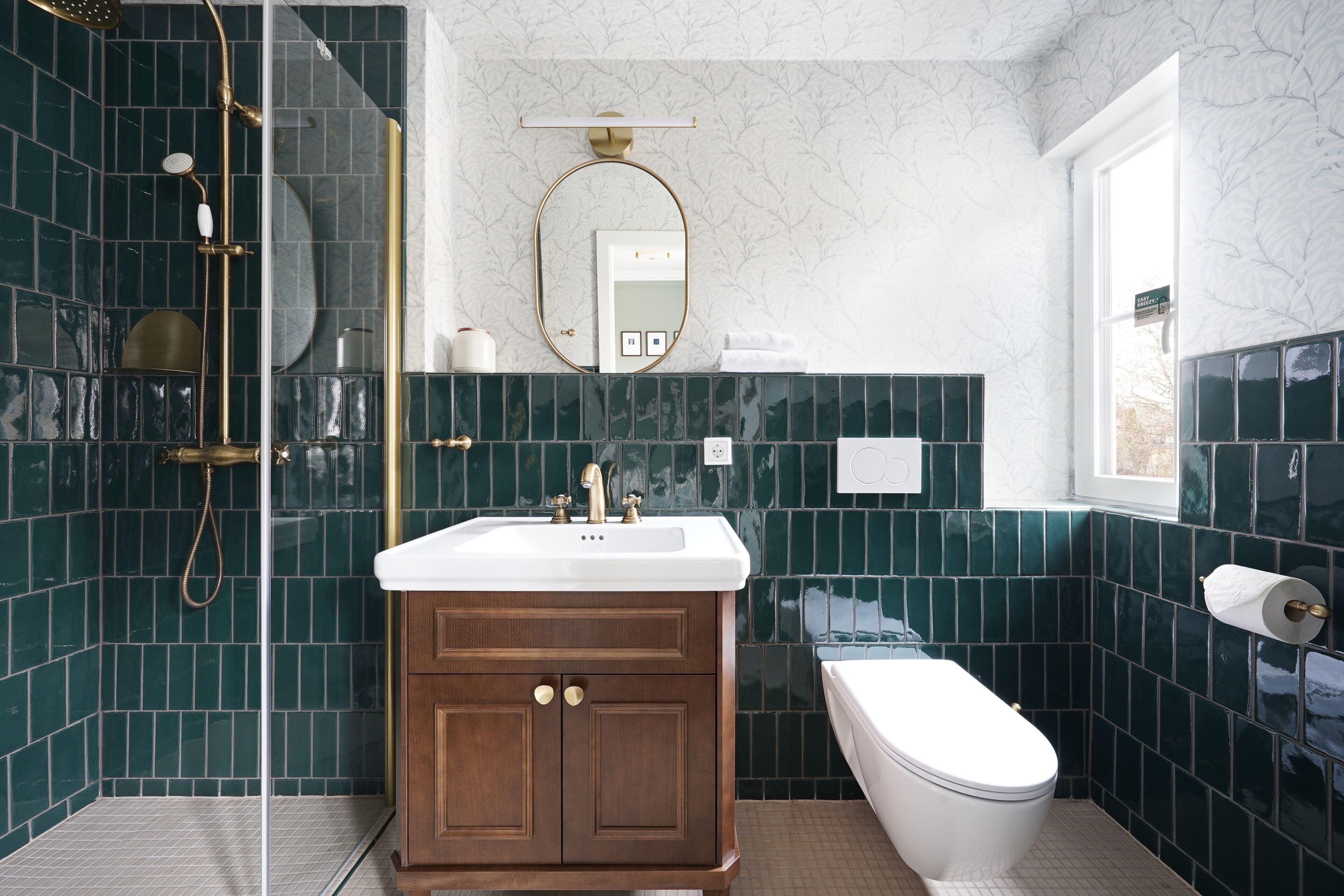 A bathroom with a shower, sink, toilet, and a mirror.