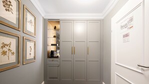 A hallway with grey cabinets, a coffee machine, and framed botanical prints on the wall. - Numa Salzburg Ivy (Anif)