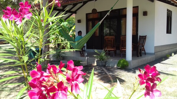 A house with a porch, a hammock, and a person sitting on the porch. - Chill Enjoy Cabanas & Restaurant (Tangalle)