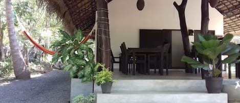 A covered outdoor area with a concrete staircase leading to a dining table and chairs.