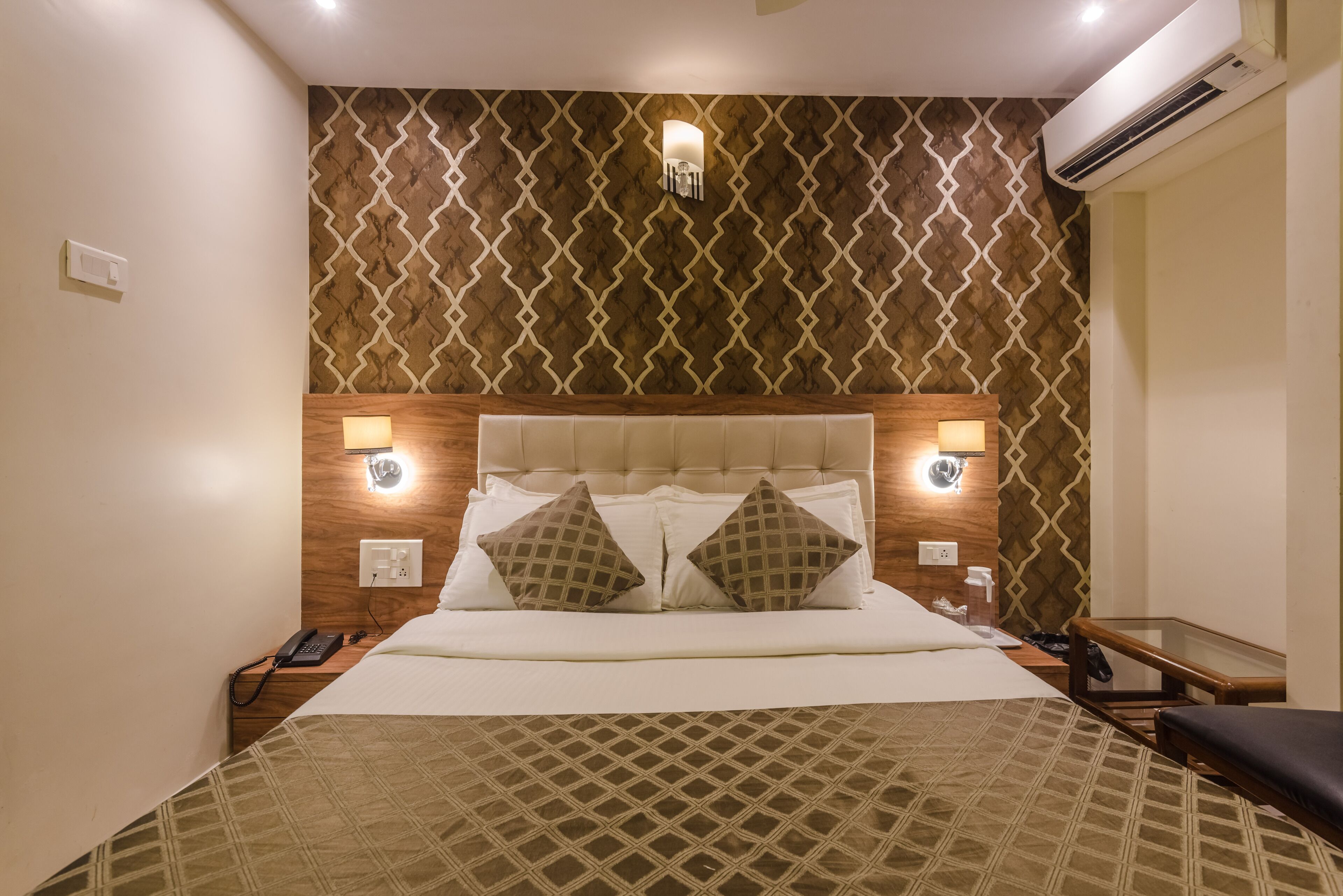 A hotel room with a bed, bedside lamps, a phone, and a small table.