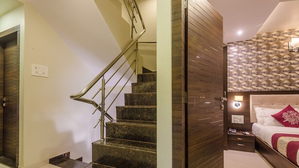 A modern hotel room with a marble staircase, a wooden accent wall, a bunk bed, and a nightstand with a lamp.