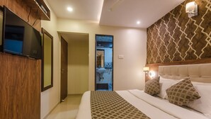 A hotel room with a large bed, a TV mounted on the wall, and a wooden panel design on the wall.
