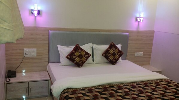 A hotel room with a bed, two bedside lamps, a bedside phone, and a small cabinet.