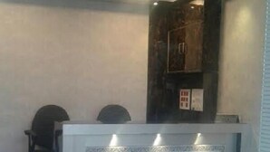 Un comptoir d’accueil portant l’inscription « KF Residency », au design moderne, avec un meuble en bois foncé et une table rouge placée au premier plan.
