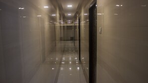 Un long couloir étroit aux murs et au sol recouverts de carreaux réfléchissants, qui mène à une porte au fond.