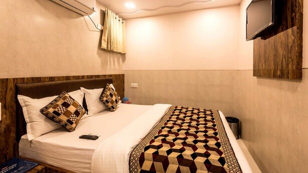 Une chambre d’hôtel équipée d’un lit, d’un téléviseur fixé au mur et d’un appareil de climatisation.