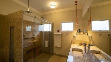 Une salle de bain moderne dotée d’une douche à parois de verre, d’un meuble-lavabo avec un plan de travail en granit et d’un grand miroir au-dessus du lavabo.