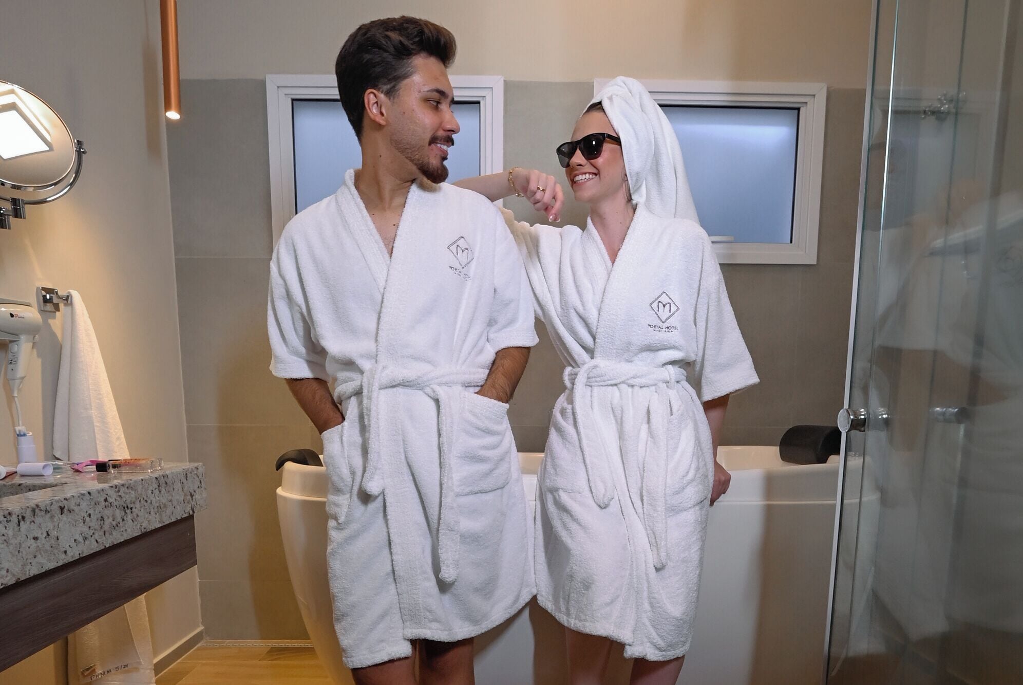 Ein Badezimmer mit Spiegel, Haartrockner und einer Duschkabine aus Glas.