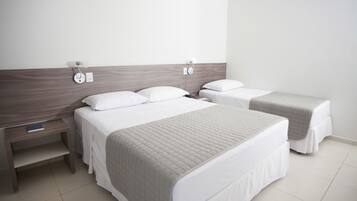 Habitación de hotel con dos camas, una mesita de noche y una lámpara de pared.
