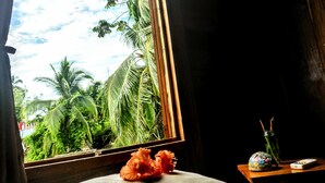 A room with a large window, a wooden table with a vase and a remote control, and a colorful object on the table. - El Jaguar (Bastimentos)